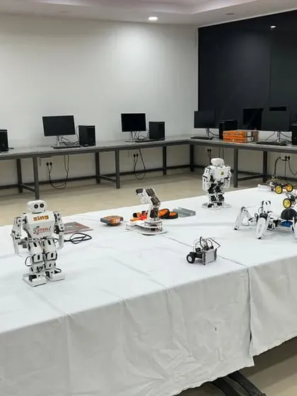 We provide a wide range of equipment to fuel student creativity. This photo shows a lab we set up, with a central table displaying various types of robots, including humanoid models, spider bots, and wheeled rovers, ready for students to program and test.