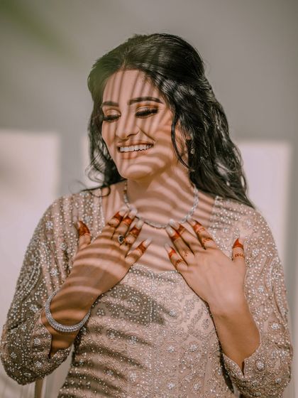 A joyful bridal portrait, with shadows from a window creating interesting patterns on her face.