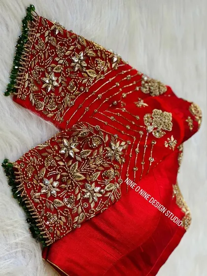 A masterpiece for our bride Madhuri. This classic red bridal blouse is heavily embroidered with zardosi and stone work, featuring a beautiful heart-shaped cutout on the back. The sleeves are a canvas of intricate floral patterns, making it a truly royal piece.