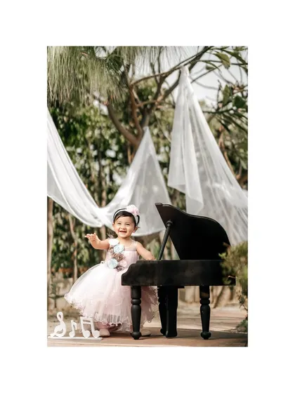 A little ballerina at her piano. Dressed in a beautiful pink tutu, this little girl is ready to dance and play in a dreamy outdoor setting.