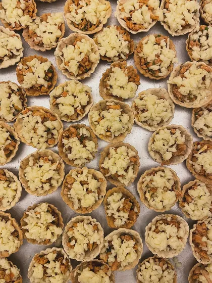 A tray of almond and herb chicken tarts being prepared. The combination of savory chicken, herbs, and crunchy almonds creates a unique texture and flavor.