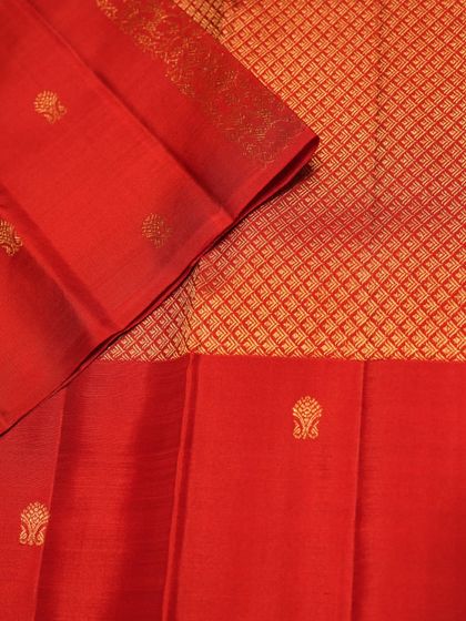 The body of the red Kanjivaram features a diamond-patterned brocade with delicate buttas, creating a rich and textured look.