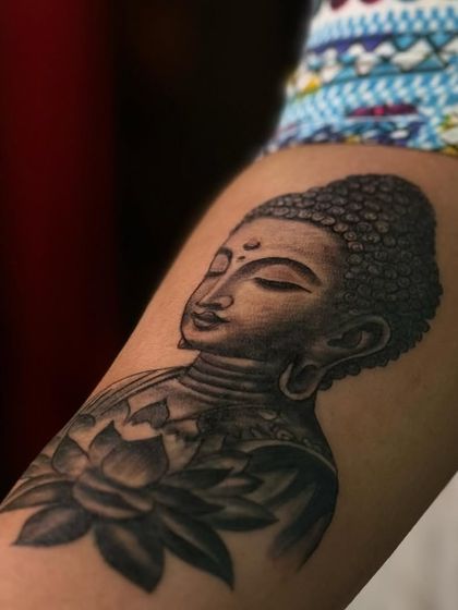 Another angle of the Gautam Buddha and lotus tattoo, highlighting the smooth black and grey shading that gives the piece depth.