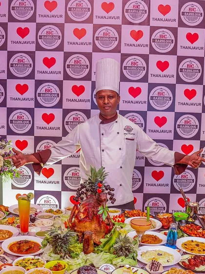 We stand by our name as the "largest buffet in town." Here's a look at the sheer scale and variety of our catering spread, featuring a chef proudly presenting dozens of multi-cuisine dishes for a grand celebration.