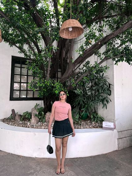 A full-length view of the sporty-chic pink tee and black skirt combo.