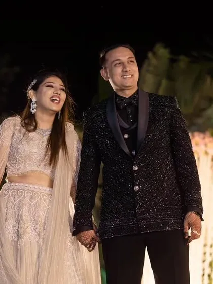 A complete groom's look for his reception. This black designer suit is covered in detailed katdana work, creating a textured, standout piece that catches the light.