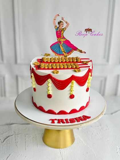A stunning cake celebrating the grace of Indian classical dance. This design is inspired by Bharatanatyam, with intricate red and gold details and a beautiful dancer topper for Trisha's birthday.