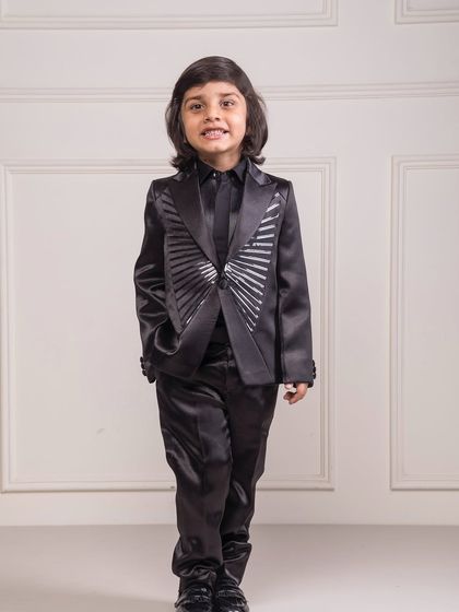 This custom tuxedo is crafted from a black satin fabric and features unique silver sunburst detailing on the jacket. It's a statement piece for any young fashion enthusiast.