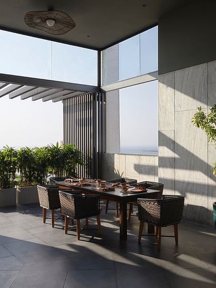 The terrace entrance, featuring a partially covered area with stone walls and a wooden pergola, opens up to expansive views of the city and sea.