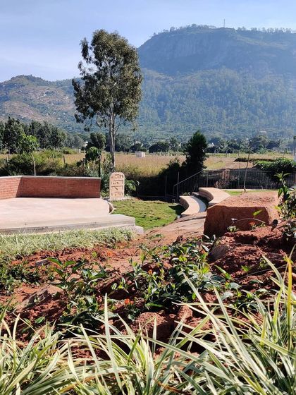 A view of the informal brick amphitheater and winding path set against the backdrop of Nandi Hills. This landscape design incorporates functional spaces for gathering while preserving the natural, rugged beauty of the site.