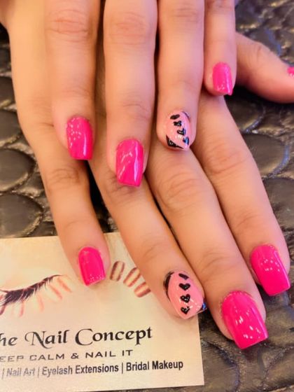 A cute and simple design on short, square nails. The bright pink polish is complemented by accent nails with a nude base and tiny, hand-painted black hearts.