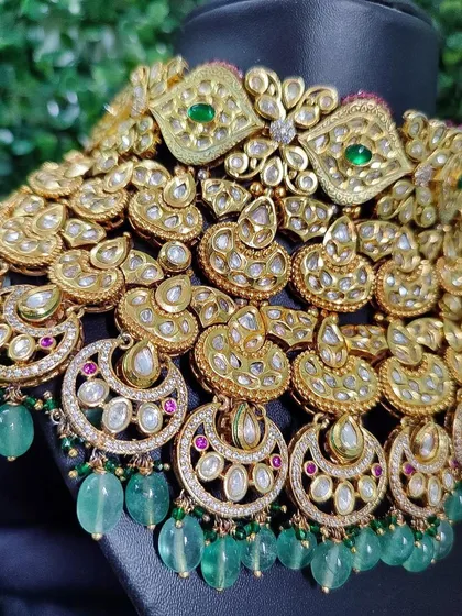 A close-up view of the intricate layers and crescent-shaped kundan work on this grand green bridal necklace.