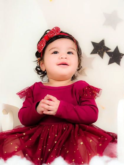 A sweet, happy moment as a baby girl claps her hands with joy in a magical, star-filled setting.