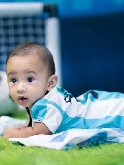 Little feet and big goals. This four-month-old is ready for the field in his football-themed sitter session.