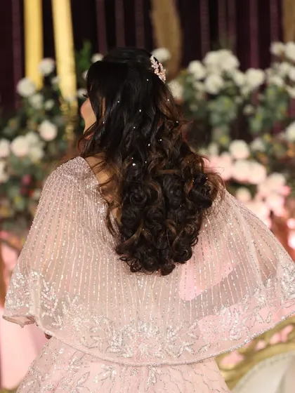 A view of the beautiful reception hairstyle. Soft curls adorned with delicate pearl accessories create a romantic and elegant finish.