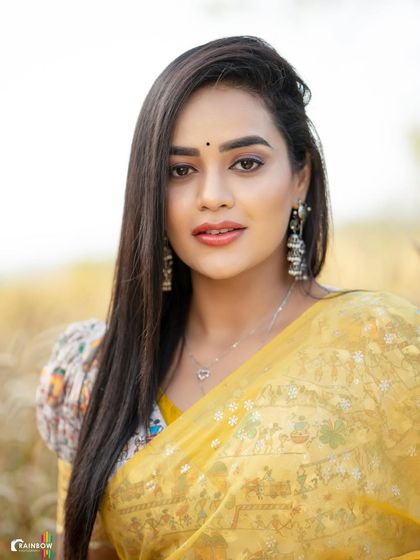 A close-up portrait in a yellow saree, shot in a field of wheat. The natural setting and warm sunlight complement the traditional attire, creating a rustic and authentic feel.