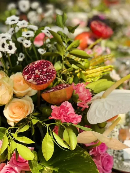 A unique centerpiece for a brunch, where fresh pomegranates are mixed with peach roses and other blooms for a touch of organic beauty.
