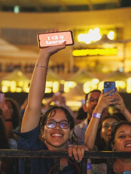 A fan holds up her phone with a message for the artist, her face lit with excitement. These are the personal connections that make a live concert feel magical.
