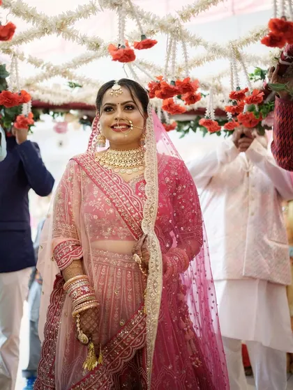 The bride making her entrance under a floral canopy. Her glowing makeup ensures she is the center of attention.