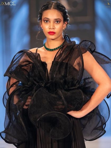 A full-length view of the stunning look from The Luxo Show. The classic red lip provides a pop of color against the voluminous black dress, creating a high-fashion moment.