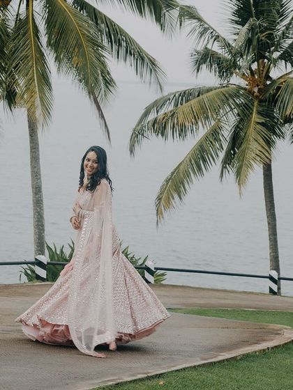 A joyful, twirling shot of Shreya on a winding path in Kovalam. This image captures her happiness and the beauty of her pastel lehenga against the lush coastal scenery.