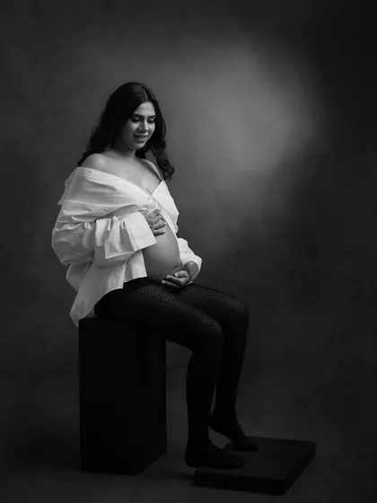 A seated portrait that feels both modern and timeless. The contrast of the white shirt against the dark background makes this black and white image truly stand out.