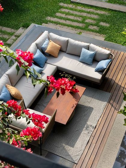 An elevated view of a comfortable outdoor lounge area on a wooden deck, surrounded by vibrant bougainvillea. This cozy corner is designed for relaxation and social gatherings, immersed in the colors of the garden.