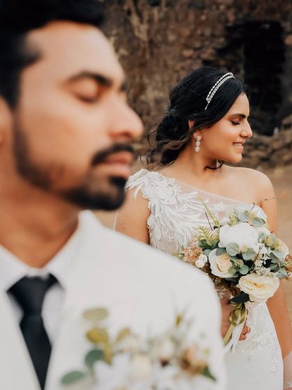 A creative shot with the groom in the foreground and the bride smiling in the background. This composition adds depth and tells a story of their connection.
