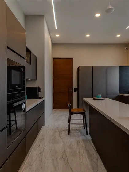 Designed for Namrata Patel, this kitchen features a metallic lacquer laminate finish in soft steel tones. The galley layout with a central island is perfect for efficient workflow.