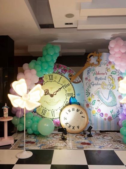 This 'Mystical Garden' version of the Alice in Wonderland theme featured a beautiful illustrated backdrop, giant clocks, and glowing flower lights. The checkerboard floor mat tied the whole whimsical scene together.