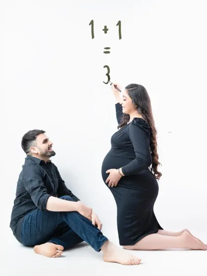 A playful and creative announcement. The mother-to-be writes "1+1=3" on a white background, a fun and simple way to share their happy news.