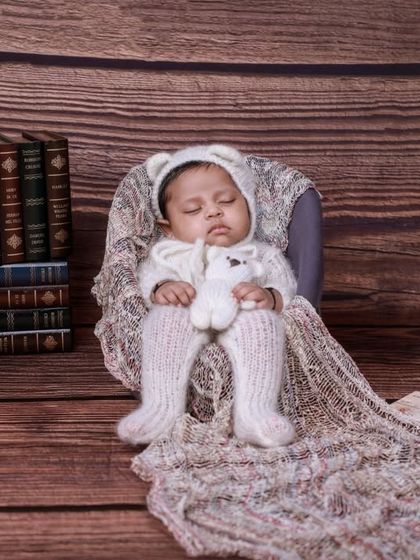 A vintage-themed setup featuring a baby in a knit outfit, surrounded by old books, a gramophone, and a rotary phone. This creates a charming, nostalgic scene.