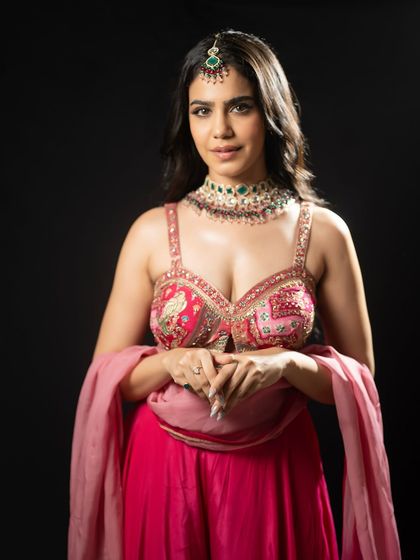 A portrait in a vibrant pink outfit, perfect for a Mehendi or Sangeet night. The look is traditional with a modern touch.