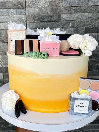 The ultimate cake for a shopaholic! This design is decorated with miniature, edible shopping bags from iconic brands like Chanel and Kate Spade, along with tiny makeup palettes, all crafted from fondant.