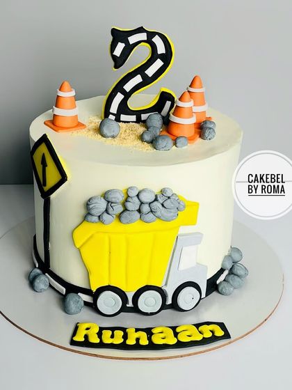 A construction-themed cake for Ruhaan's 2nd birthday, featuring a dump truck, traffic cones, and edible gravel.