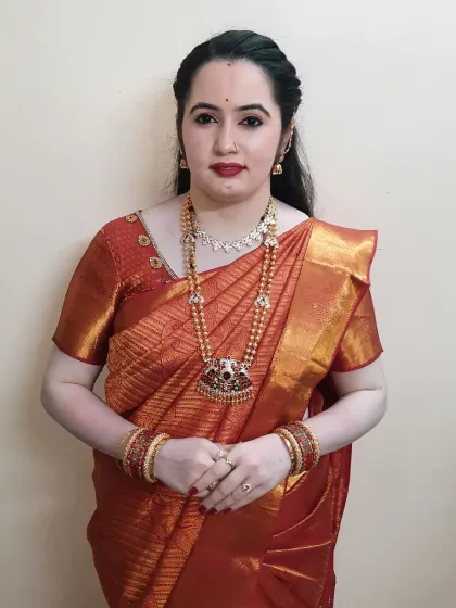 A full-length view of the client's look for the party. The simple makeup and hair allow her beautiful orange silk saree and traditional jewellery to take center stage.