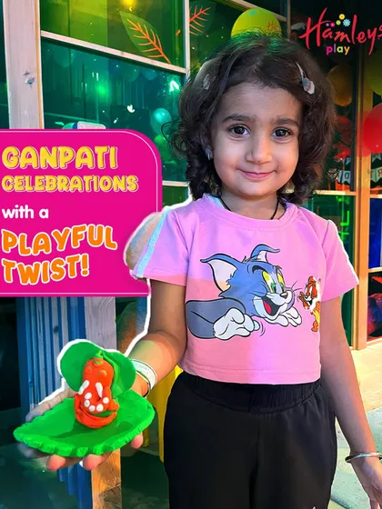 A young girl holds up her colorful clay Ganpati, made with her own two hands. Our workshops are all about giving kids a playful and memorable festive experience.