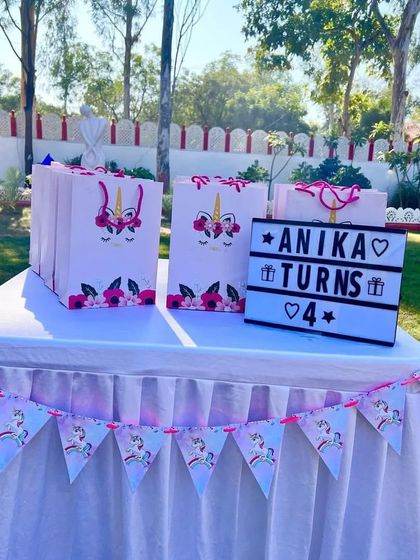 Themed party favors are a must! These unicorn-themed gift bags and a custom lightbox sign were part of a beautiful outdoor setup.