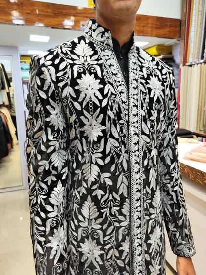 A client trying on his custom-made black and white embroidered open sherwani. This piece is a perfect example of how we bring bold, celebrity-inspired designs to life.