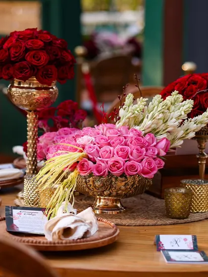 A close-up of a table centerpiece. I believe luxury is in the details, like these lush arrangements of red and pink roses in ornate golden vases, which add a touch of opulence to every table.