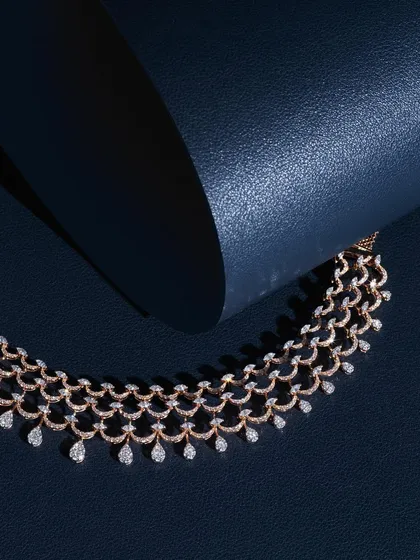 A more conceptual shot of the diamond necklace, using a curved piece of blue leather to interact with the jewelry. The shadow and light create a dynamic composition that feels modern and elegant.