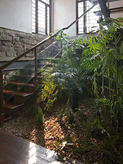 Details are everything in creating a truly organic space. Here, a staircase made of local wood is set against a wall of stone recovered from the site, with an indoor garden of river gravel and native plants thriving below. It's a celebration of natural, locally sourced materials.