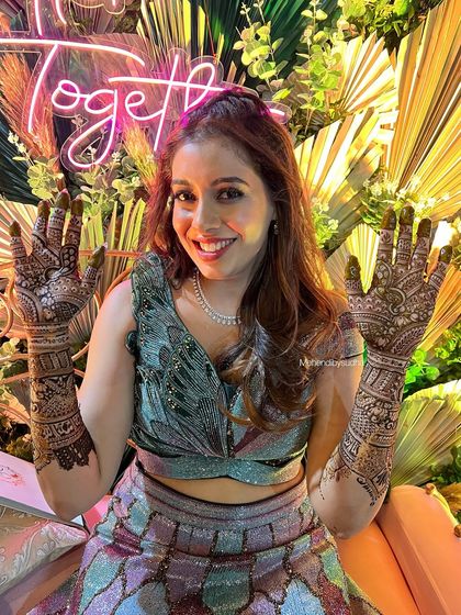 A full, happy portrait of the bride with her unique and modern bridal mehendi.