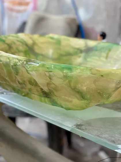 An in-progress shot of a green and white resin basin, with an organic, sculpted shape. This piece is still on the workbench but already showing its unique character.