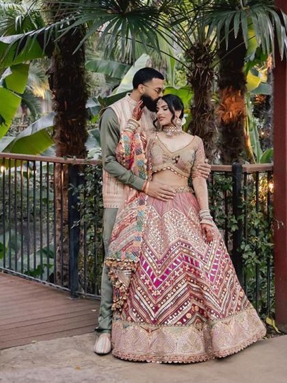 An intimate moment during their Jaggo night. The bride's vibrant, multi-colored lehenga is perfectly balanced by the groom's subtle olive green and beige outfit.