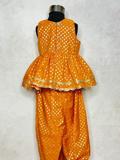 The back view of the girl's peplum top from the yellow sibling set, showing the simple button closure that makes it easy to wear.