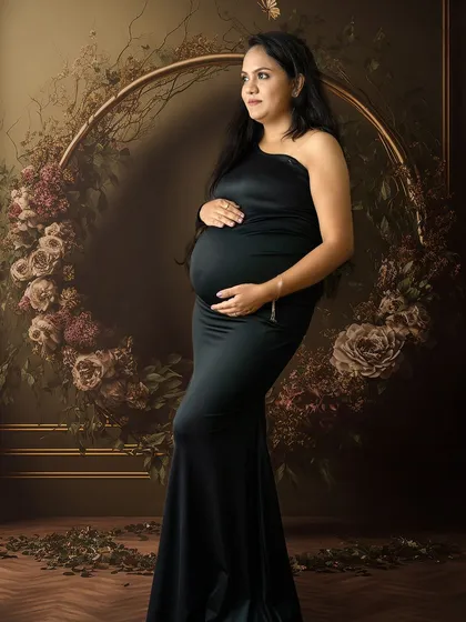 A classic maternity pose in a black gown, with the mom-to-be framed by a dark floral hoop for a touch of romantic drama.