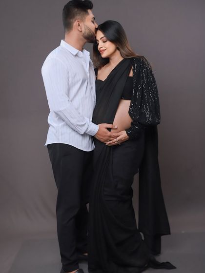 A gentle and loving pose. The dad-to-be kisses his partner's head while they both cradle the baby bump, a perfect example of a tender "tere naal" moment.