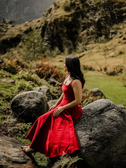 A solo portrait of the bride-to-be, looking out at the Manali landscape, dressed in a stunning red gown.