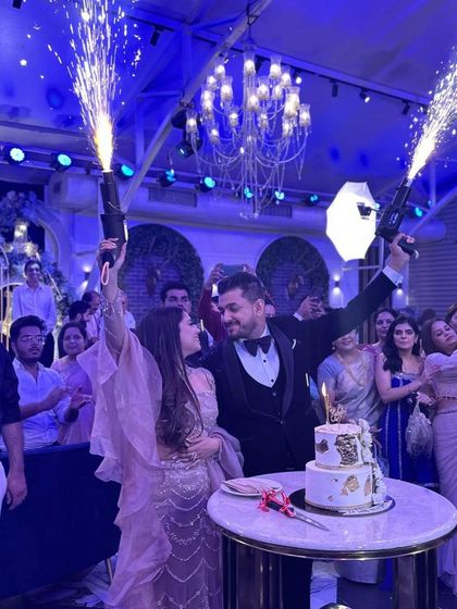 A magical moment from a Roka ceremony, with the couple celebrating with sparklers and one of my two-tiered white and gold floral cakes.